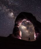 person under delicate arch at night