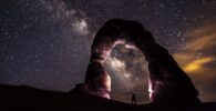 person under delicate arch at night