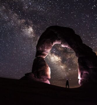 person under delicate arch at night
