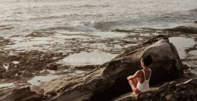 photo of woman sitting on rock