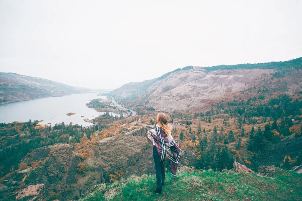 unrecognizable female tourist admiring lake in mountains