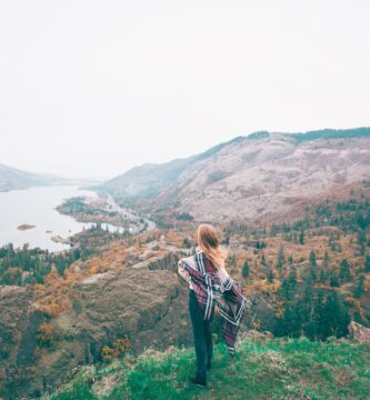 unrecognizable female tourist admiring lake in mountains