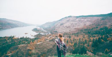 unrecognizable female tourist admiring lake in mountains
