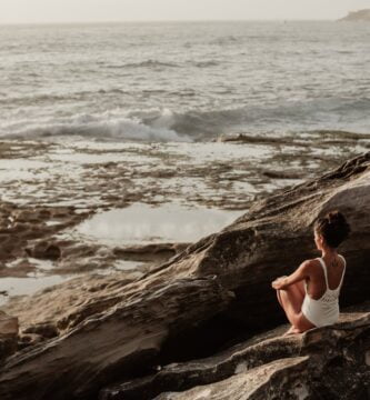 photo of woman sitting on rock