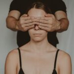 crop man covering eyes of anonymous woman