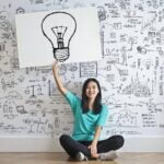 woman draw a light bulb in white board