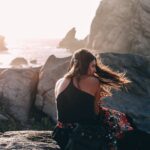 calm woman on rocky seashore on windy day