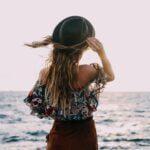 stylish woman enjoying windy day on coast