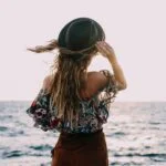 stylish woman enjoying windy day on coast