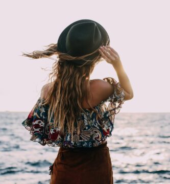 stylish woman enjoying windy day on coast